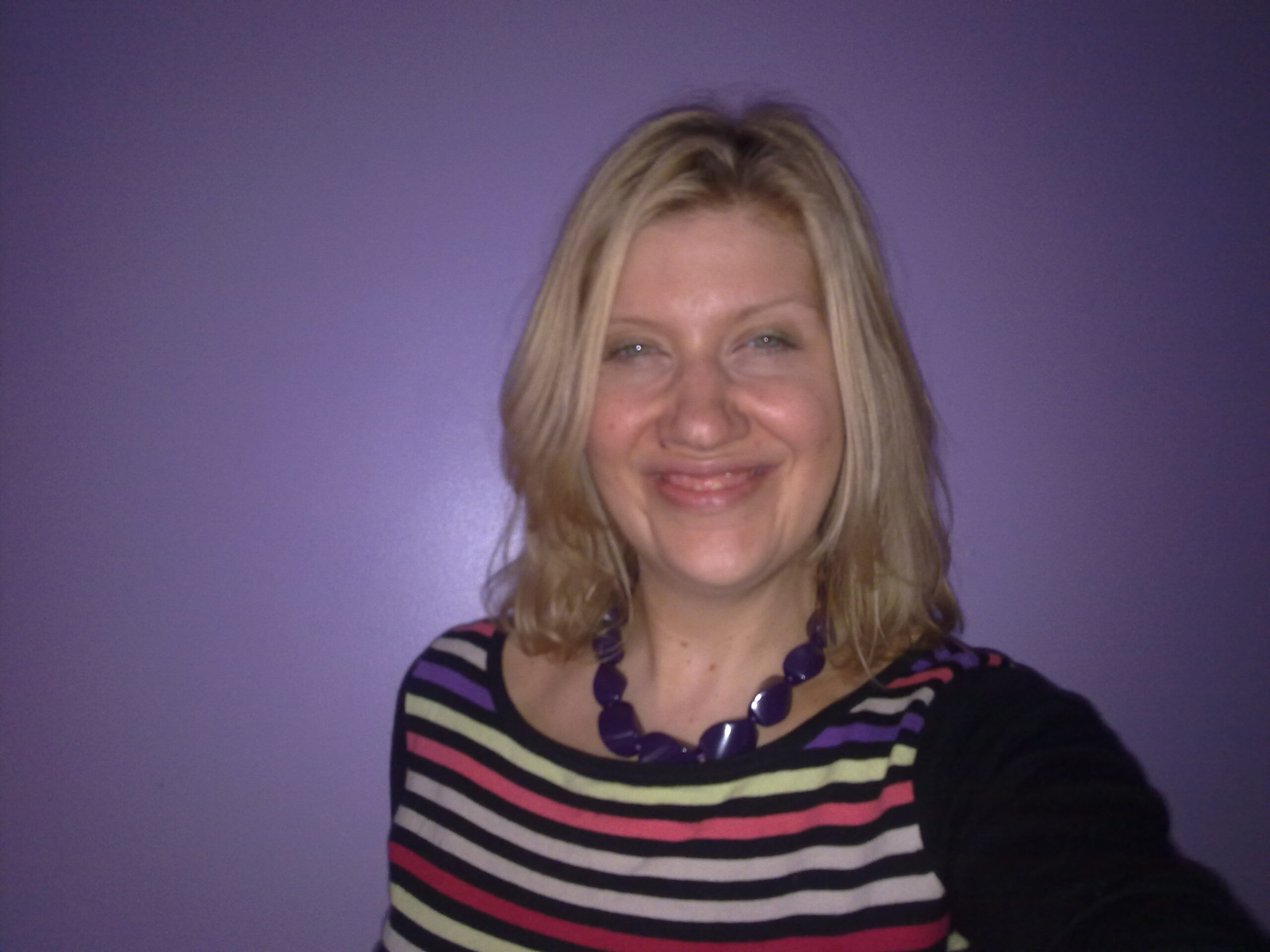 A picture of Melanie Vella, standing against a purple background